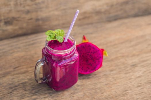 Smoothies of a red organic dragon fruit on an old wooden background.