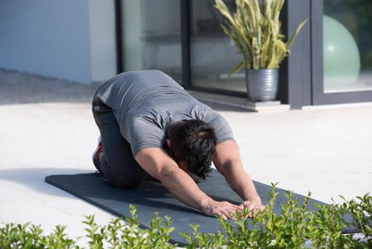 young handsome man doing morning yoga exercises in front of his luxury home villa