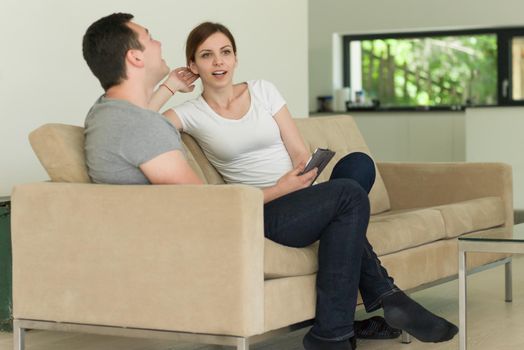 Young couple relaxing at luxurious home with tablet computers reading in the living room on the sofa couch.