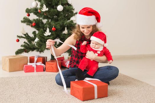 Family, childhood and Christmas concept - Portrait of happy mother and adorable baby in suit of Santa.