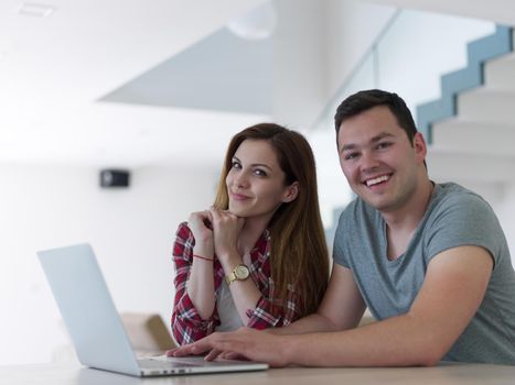 happy young couple buying online using laptop a computer and a credit card in their luxury home villa