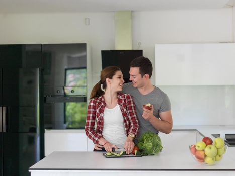 Young handsome couple in the kitchen  beautiful woman preparing a salad while the man eating an apple