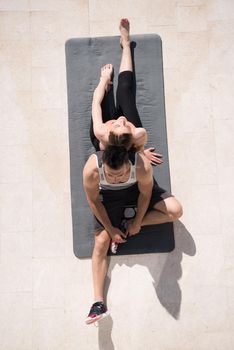 young handsome woman with personal trainer doing morning yoga exercises in front of her luxury home villa top view