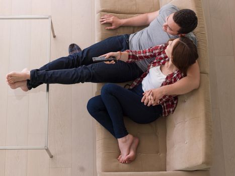 Young couple on the sofa watching television together in their luxury home