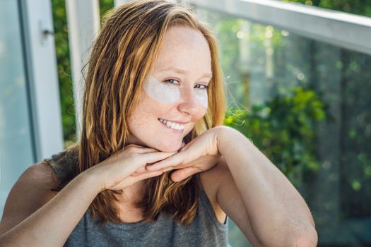 Portrait of Beauty Red-haired woman with eye patches showing an effect of perfect skin. Spa Girl.