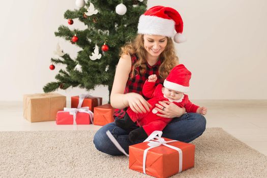 Family, childhood and Christmas concept - Portrait of happy mother and adorable baby in suit of Santa.