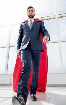 businessman in a Superman cloak standing in a bright office.photo with copy space
