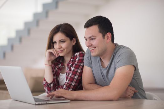 happy young couple buying online using laptop a computer and a credit card in their luxury home villa