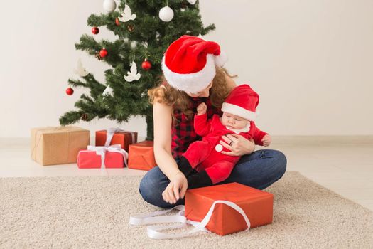 Family, childhood and Christmas concept - Portrait of happy mother and adorable baby in suit of Santa.