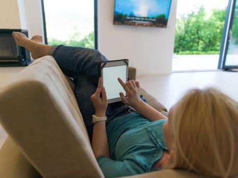 young happy woman on sofa using tablet computer at luxury home