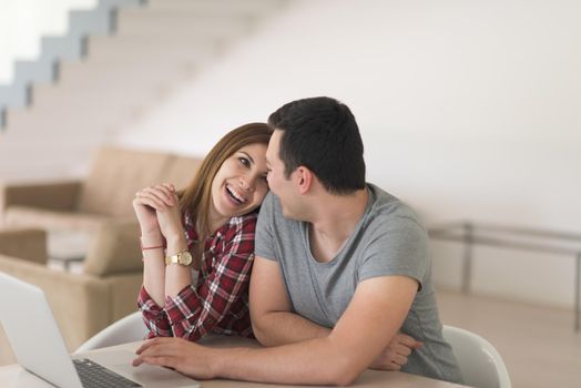 happy young couple buying online using laptop a computer and a credit card in their luxury home villa