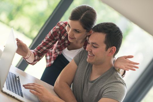 happy young couple buying online using laptop a computer and a credit card in their luxury home villa