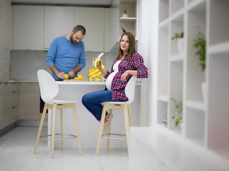 young pregnant couple cooking food fruit lemon juice at kitchen, lifestyle healthy pregnancy happy life concept