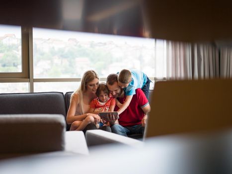 Happy Young Family Playing Together with tablet at home sitting on the sofa