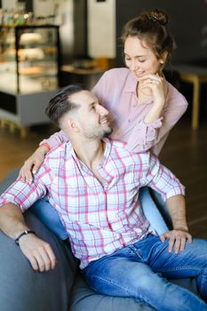 Happy pretty husband sitting with nice wife at home. Concept of spending time together and relationship.