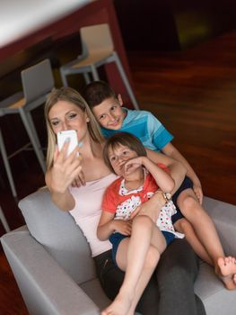 Happy family siting on sofa and using cell phone for video call  at home