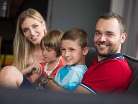 Happy Young Family Playing Together with tablet at home sitting on the sofa