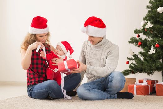Holidays, children and family concept - Happy couple with baby celebrating Christmas together at home