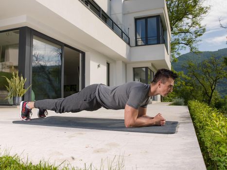 young handsome man doing morning yoga exercises in front of his luxury home villa