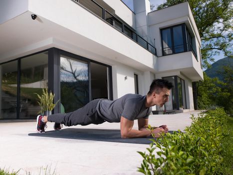 young handsome man doing morning yoga exercises in front of his luxury home villa