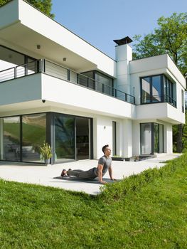 young handsome man doing morning yoga exercises in front of his luxury home villa