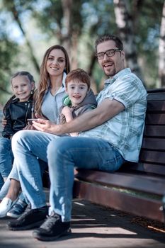 happy family sitting on bench in summer Park.the concept of family entertainment