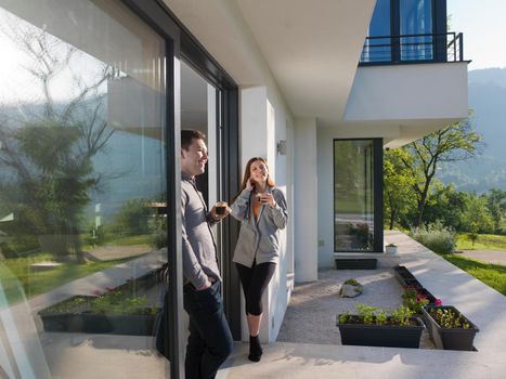 young beautiful handsome couple enjoying morning coffee on the door of their luxury home villa