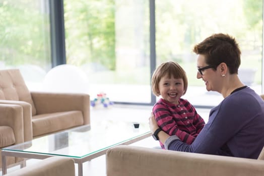 young mother and cute little girl enjoying their free time hugging on the sofa in their luxury home villa