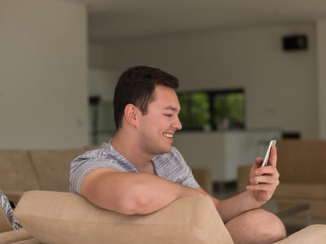 Handsome casual young man using a mobile phone at luxurious home