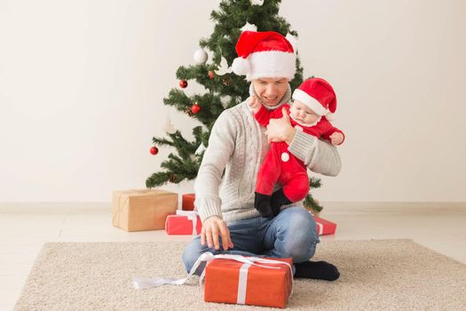 Father with his baby boy wearing Santa hats celebrating Christmas