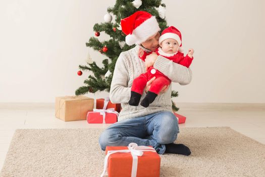 Father with his baby boy wearing Santa hats celebrating Christmas