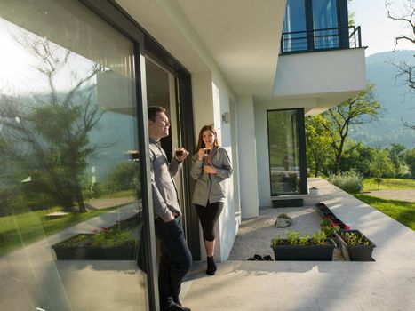 young beautiful handsome couple enjoying morning coffee on the door of their luxury home villa