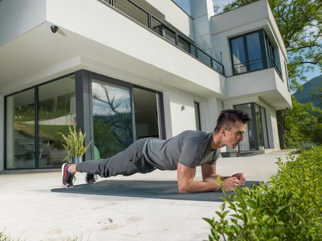 young handsome man doing morning yoga exercises in front of his luxury home villa