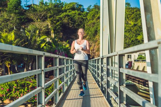 Beautiful woman running over bridge during sunset.