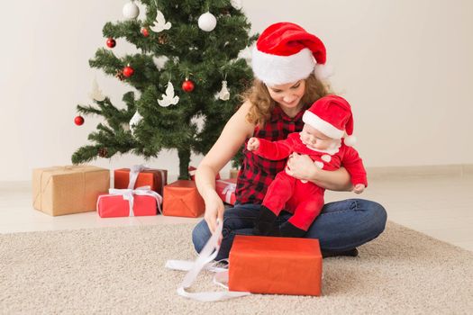 Family, childhood and Christmas concept - Portrait of happy mother and adorable baby in suit of Santa.