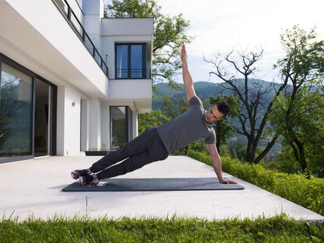 young handsome man doing morning yoga exercises in front of his luxury home villa