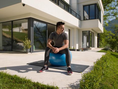 young handsome man doing morning yoga exercises in front of his luxury home villa