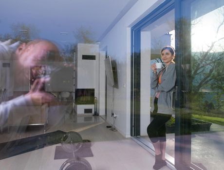 portrait of a young beautiful successful woman drinking coffee in the doorway of her luxury home villa