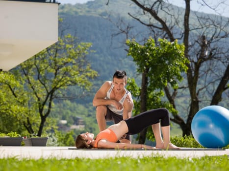 young handsome woman with personal trainer doing morning yoga exercises in front of her luxury home villa