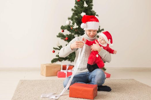 Father with his baby boy wearing Santa hats celebrating Christmas