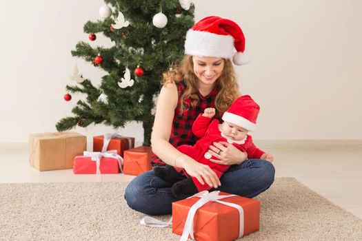 Family, childhood and Christmas concept - Portrait of happy mother and adorable baby in suit of Santa.