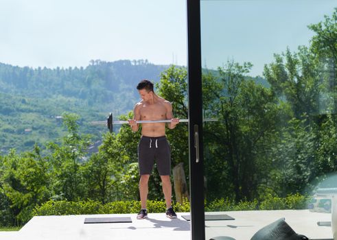 young handsome man doing morning exercises in front of his luxury home villa