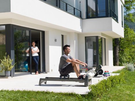 young handsome man doing morning exercises in front of his luxury home villa