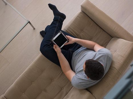 young happy man on sofa using tablet computer at luxury home