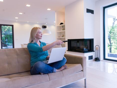 Young woman using her laptop computer in her luxury modern home, smiling