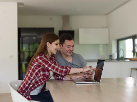 happy young couple buying online using laptop a computer and a credit card in their luxury home villa