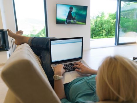 Young woman using her laptop computer in her luxury modern home, smiling