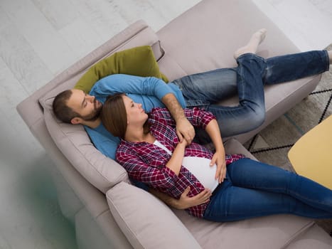 top view of happy pregnant couple relaxing on sofa couch at home