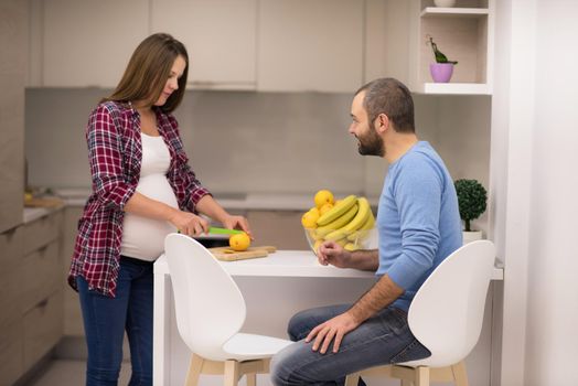 young pregnant couple cooking food fruit lemon juice at kitchen, lifestyle healthy pregnancy happy life concept