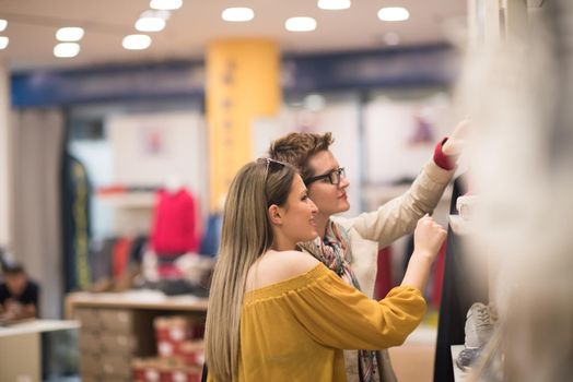 Two Girl-Friends On Shopping Walk On Shopping Centre With Bags And Choosing